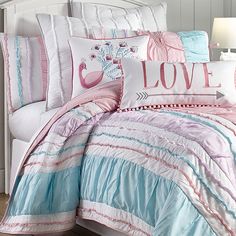 a bed with pink, blue and white comforters on it