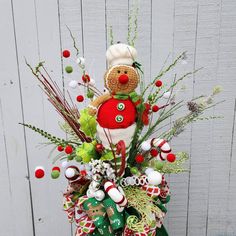 a christmas arrangement in a basket on top of a wooden table next to a fence