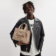 a man holding a bag with the word coach on it