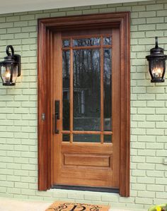 a wooden front door with two lights on the side