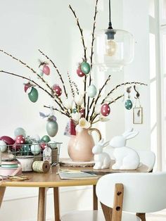 a dining room table with easter decorations and eggs in a vase on the table next to it