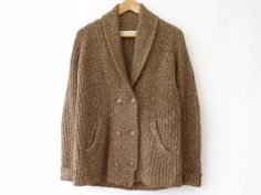 Brown tweed, ribbed knit, shawl collar cardigan by Zara. Cardigan has front pockets, double breasted button closure and corduroy elbow patches. Sweater is soft and not itchy. Condition/flaws: Cardigan is in overall excellent. Bottom ribbing appears to be stretched out so it has a bit of a loose fit. Also, front sides do not perfectly align at the bottom front centre (see photo). Fibre Content: 59% acrylic 27% cotton 14% nylon Garment Care: Hand wash, do not tumble dry, low iron, do not dry clean Cozy Shawl Collar Cardigan For Work, Winter Shawl Collar Cardigan With Buttons, Fall Cable Knit Sweater Coat With Shawl Collar, Workwear Sweater With Button Closure And Shawl Collar, Zara Cardigan, Knit Shawl, Shawl Collar Cardigan, Brown Tweed, Sweater Fits