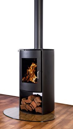 a black stove sitting on top of a wooden floor next to a pile of wood