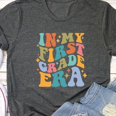 THE STORY Show your Swiftie pride and get your entire grade level team shirts. PLUS customize it with teacher names for only $1 extra (just message us for more information) THE FIT True-to-fit. If you prefer a looser fit, we recommend ordering one size larger than normal. SPECS "Printed on Bella Canvas short-sleeve crew neck in Heather Dust, Deep Heather Gray, Dark Grey Heather or Heather Black" 52/48 combed ring-spun cotton/polyester CARE INSTRUCTIONS Machine wash cold, inside out, with like co Multicolor Letter Print T-shirt For School Events, School Spirit T-shirt With Name Print For Teacher Appreciation, Crew Neck T-shirt With Name Print For School Events, Multicolor Letter Print Tops For School Events, College Fun School Spirit T-shirt With Funny Text, School Spirit T-shirt For School Events, School Spirit T-shirt With Text Print For School Events, Back To School Spirit T-shirt With Name Print, School Spirit T-shirt With Text Print For Teacher Appreciation