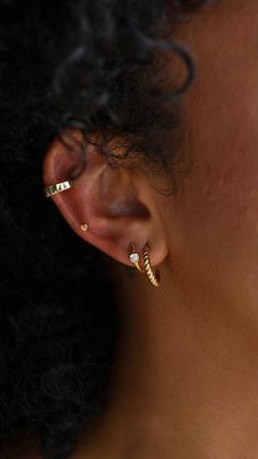 a close up of a woman's ear wearing gold earrings