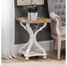 a white table with a plant on top and a chair in the corner behind it