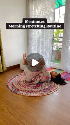 a woman sitting on the floor in front of a window with her hands up to her face