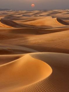 the sun is setting over some sand dunes