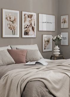 a bedroom with pictures on the wall and a bed covered in linens next to a window