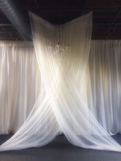 a room with white drapes and chandelier hanging from the ceiling