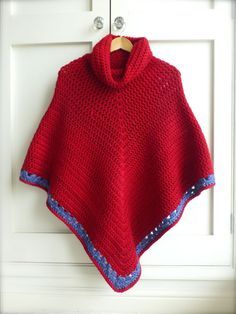 a red crocheted ponchle hanging on a white door