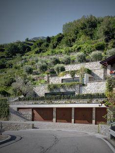 a car parked in front of a house on the side of a hill with lots of greenery