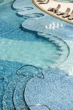 an empty swimming pool with lounge chairs in the middle and water running down it's sides