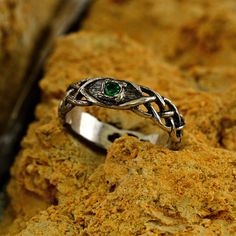 a silver ring with a green stone in the middle on top of some rock formations