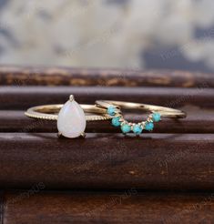 two gold rings with opalite and turquoise stones on wooden surface, close up