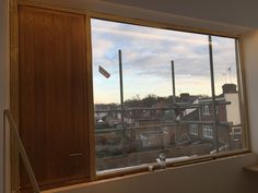 an open window with the view of some houses in the distance and buildings behind it