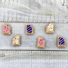 four decorated cookies sitting on top of a wooden table with frosting and sprinkles