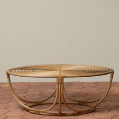 an oval coffee table made out of wicker and bamboo with curved legs on a brick floor