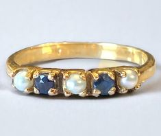 three stone ring with blue and white stones on each side, set in yellow gold