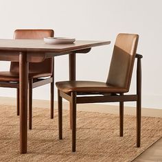 a wooden table with two chairs and a bowl on it next to a brown rug