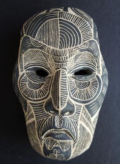 a black and white mask with an intricate design on it's face, against a dark background