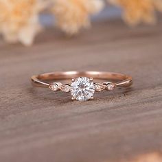 a rose cut diamond engagement ring on top of a wooden table with flowers in the background