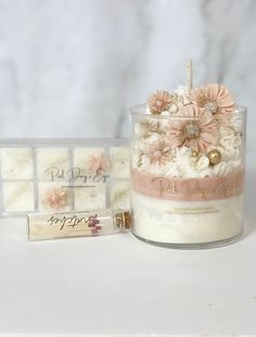 a small candle with flowers on it next to some soaps and a card holder