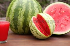 a watermelon and a glass of juice sitting on a table next to each other