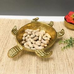 a gold turtle shaped bowl filled with peanuts