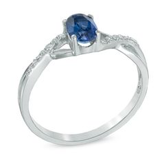 an oval blue sapphire and diamond ring on a white background with diamonds around the band