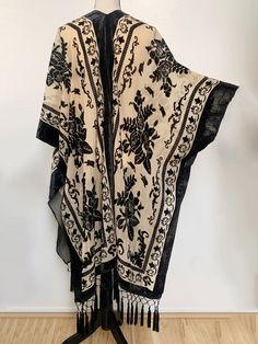 This shawl is absolutely LUSH...very reminiscent of fabulous piece from early 1900s. Would work beautiful over a nice dress or as a robe. The fabric is slightly sheer golden nude with an all over black velvet floral pattern and trim. All along the bottom is lovely diamond fringe to really seal the glamorous look of this piece. It is one size fits all (yes, really! S-5X) and does feature armholes for ease of wear. It is NOT at all fitted and it does have armholes and it functions more like a cape Luxury Bohemian Shawl For Festive Occasions, Affordable Vintage Women's Shawl, Luxury Black Shawl With Floral Embroidery, Luxury Bohemian Shawl With Fringe, Luxury Black Shawl With Motifs, Festival Black Shawl Kimono, Elegant Festival Kimono, Shawl Fashion, Shawl Cardigan