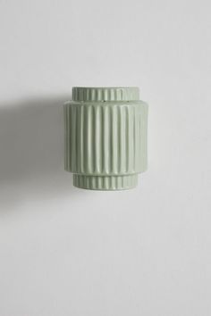 a green vase sitting on top of a white wall