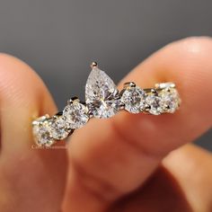 a close up of a person holding a ring with three pear shaped diamonds on it