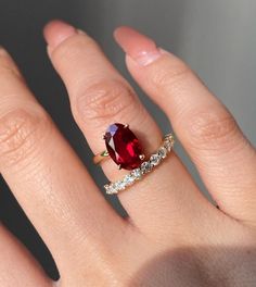 a woman's hand with a ring on it and a red stone in the middle