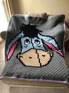 a crocheted blanket with a dog's face on it, sitting on a couch