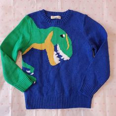 a blue sweater with an image of a dinosaur on it