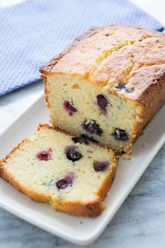 a loaf of lemon blueberry bread on a white plate with a blue towel and napkin