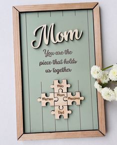 a wooden puzzle frame with the words mom on it and flowers in front of it