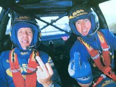 two people sitting in the back of a car with helmets on and pointing at something