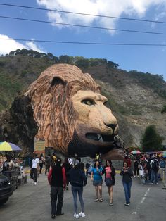 people are walking around in front of a giant lion head