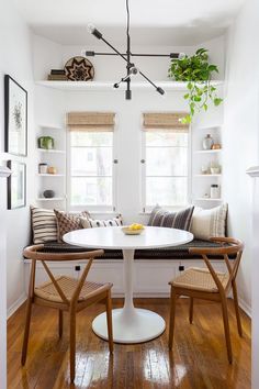 a white table with two chairs and a bench in the middle of a room that has wood flooring