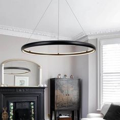 a living room filled with furniture and a fire place under a circular light hanging from the ceiling