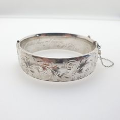 "A quality vintage sterling silver snap bangle bracelet with wavy leaf like pattern on the front and a plain smooth back. The bracelet is fully hallmarked with date letter \"Q\" dating to 1975 and opens and closes as it should. It measures internally approx. 6.10 cm internally to fit on your wrist and it is approx. 19 mm wide. it has a nice heavy weight of 47g. there are minor surface scratches on the inside and to the rear, the face side is in good condition and there are no dents. The inside has an engraved message \" To Gill wishing you every happiness\" Please check out the other items in my shop. Be sure to view all photos and videos for condition and read the titles and descriptions. Sizes are in the latter photos.  Don't hesitate to send me a message with any queries. All my items a Luxury Etched Silver Bangle, Classic Engraved Sterling Silver Bangle Bracelet, Classic Silver Engraved Bangle, Vintage Sterling Silver Bracelet For Wedding, Vintage Sterling Silver Bracelet For Anniversary With Polished Finish, Vintage Engraved White Gold Bracelets, Vintage Sterling Silver Bracelet In White Gold For Wedding, Victorian Silver Engraved Bangle, Victorian Style Silver Engraved Bangle