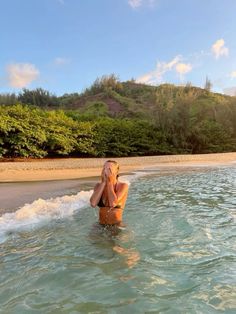 a woman is sitting in the water at the beach