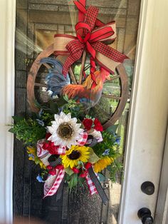 a wreath on the front door decorated with sunflowers, daisies and feathers