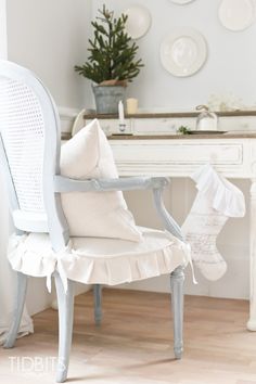 a white chair sitting in front of a table with christmas decorations on the wall behind it