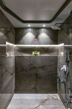 a bathroom with marble walls and flooring in the shower area is lit by recessed lighting