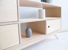 a white vase sitting on top of a wooden shelf next to a wall mounted cabinet