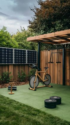 a bike and exercise equipment in a backyard with solar panels on the fence behind it