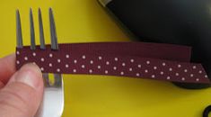 a person is holding a fork and knife with polka dot ribbon on the end of it